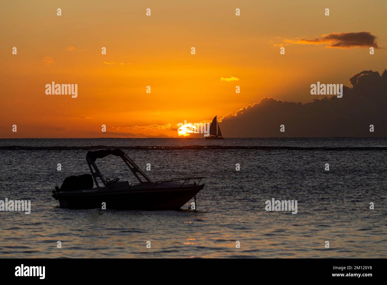 Una barca solitaria nell'oceano - e una nave a vela all'orizzonte durante il tramonto dell'Isola Mauritius, Africa Foto Stock