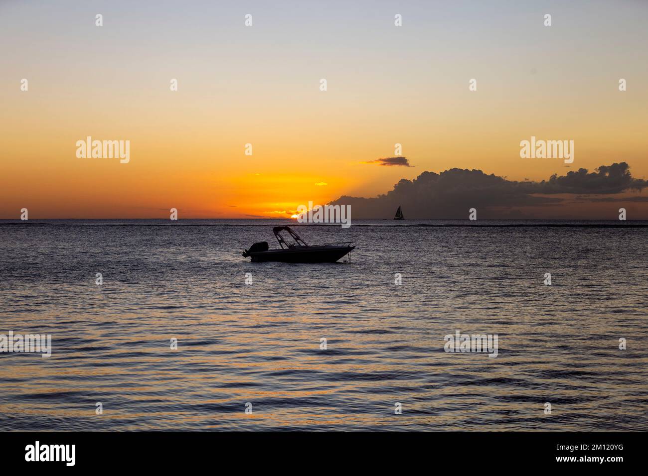 Una barca solitaria nell'oceano - e una nave a vela all'orizzonte durante il tramonto dell'Isola Mauritius, Africa Foto Stock