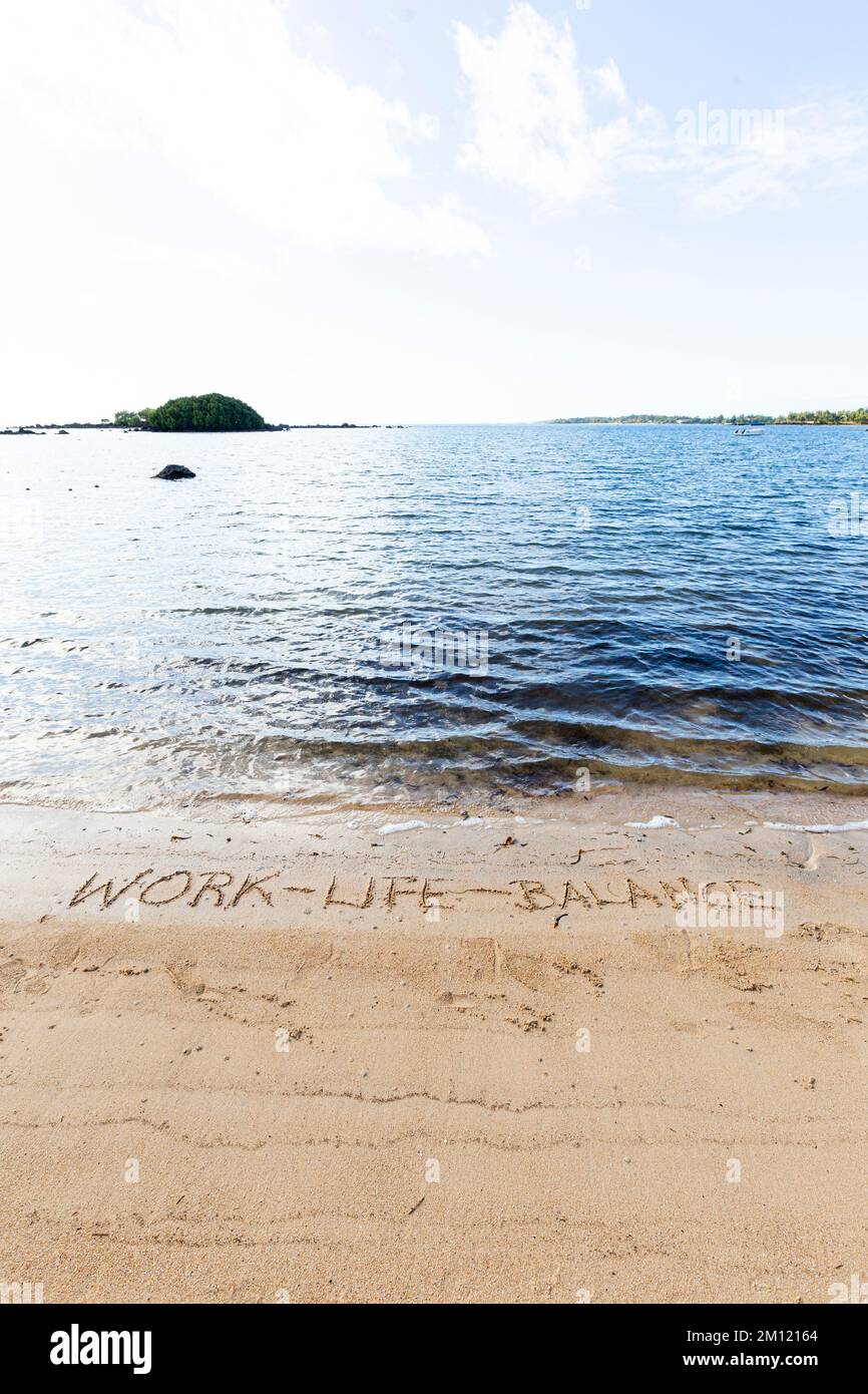 Lavoro-vita-equilibrio - come un messaggio scritto con un dito nella sabbia su una spiaggia con le onde e l'oceano blu a Mauritius Island, Africa, vista dall'alto, nessuno Foto Stock