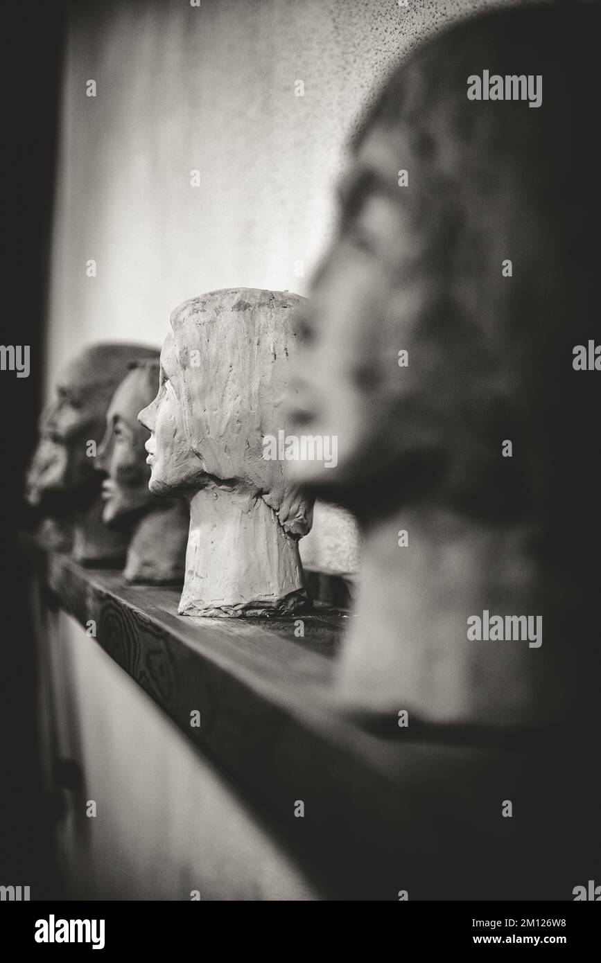 Sculture in forma di teste umane affiancate su un bordo Foto Stock