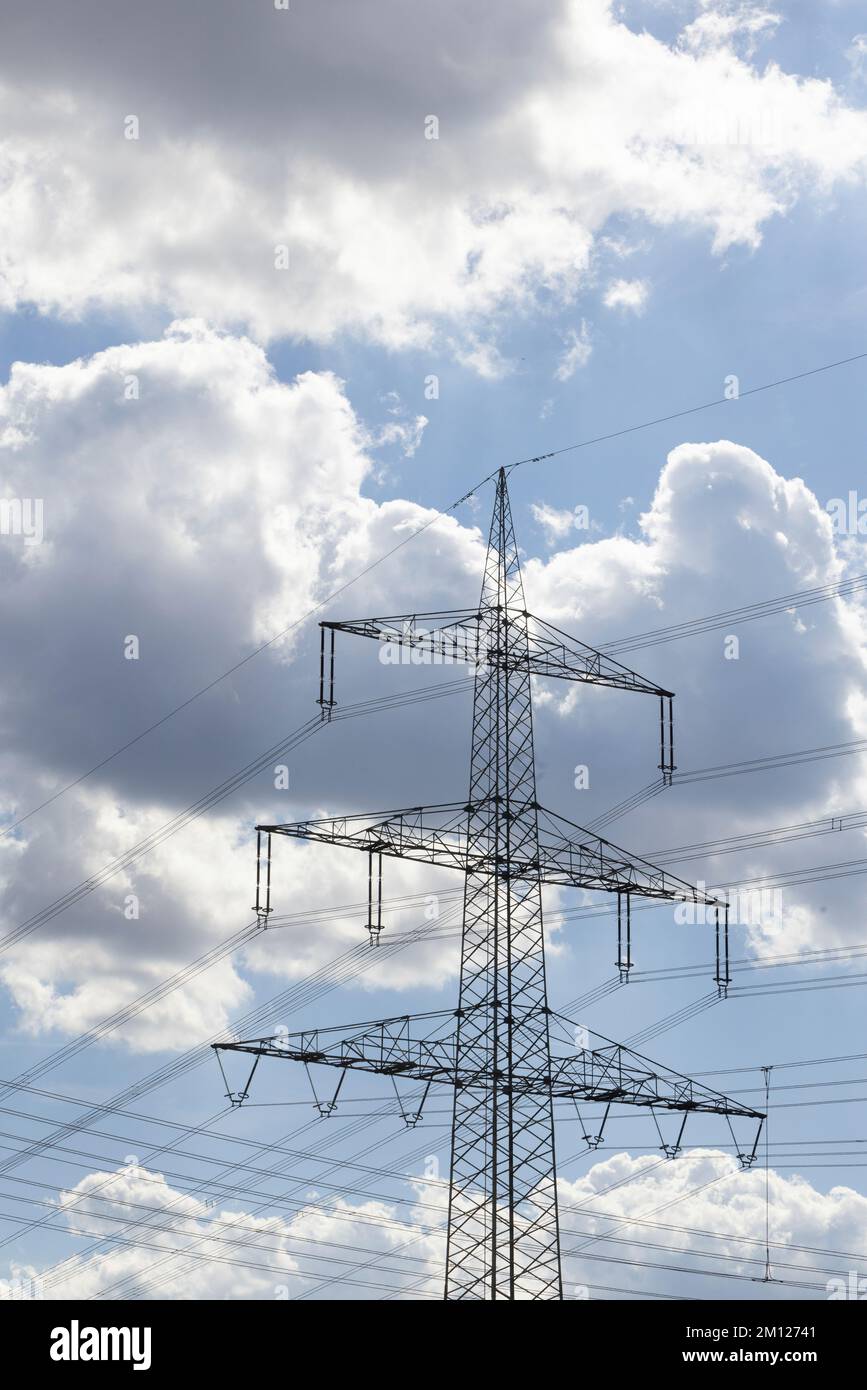 Parte superiore del pilone elettrico contro il cielo blu con le nuvole di pioggia in Germania Foto Stock