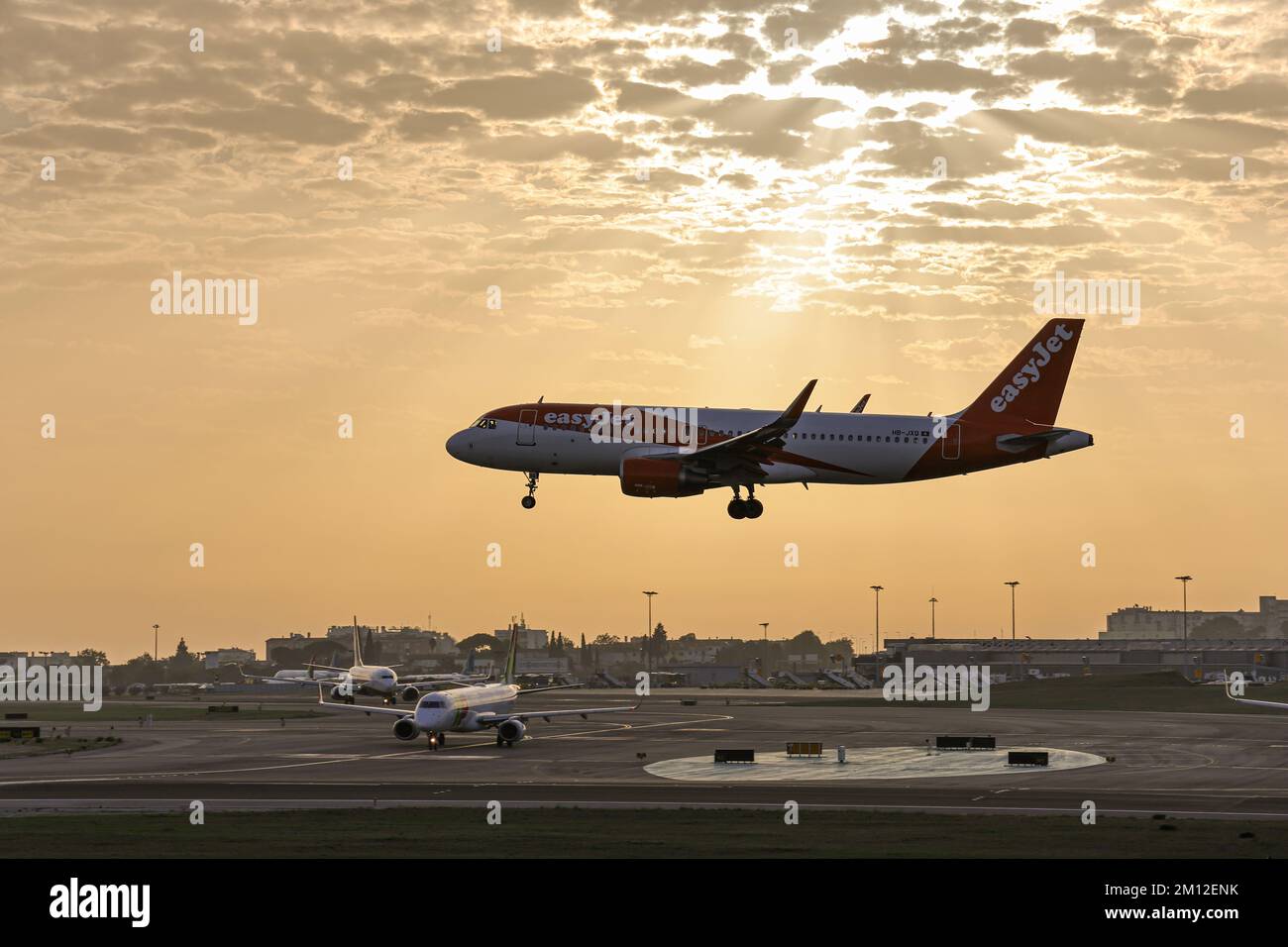La vista di una compagnia aerea EasyJet Airbus che atterra all'aeroporto Humberto Delgado al tramonto Foto Stock