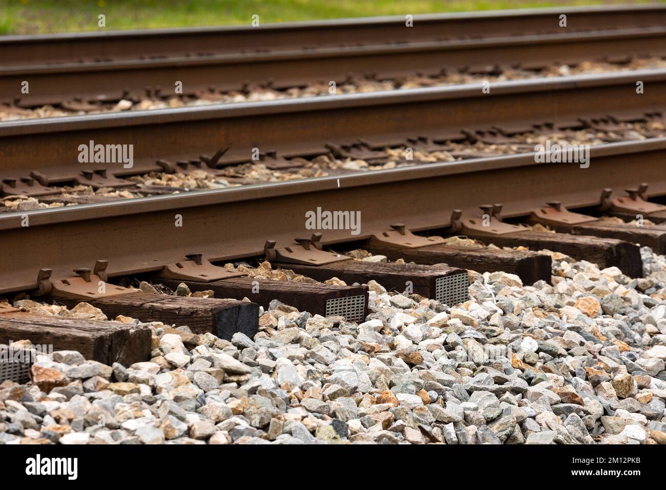 Un dettaglio teleobiettivo di due linee ferroviarie moderne, con punte, lacci in legno e piastre di supporto in metallo. Come si trova tipicamente negli Stati Uniti. Foto Stock