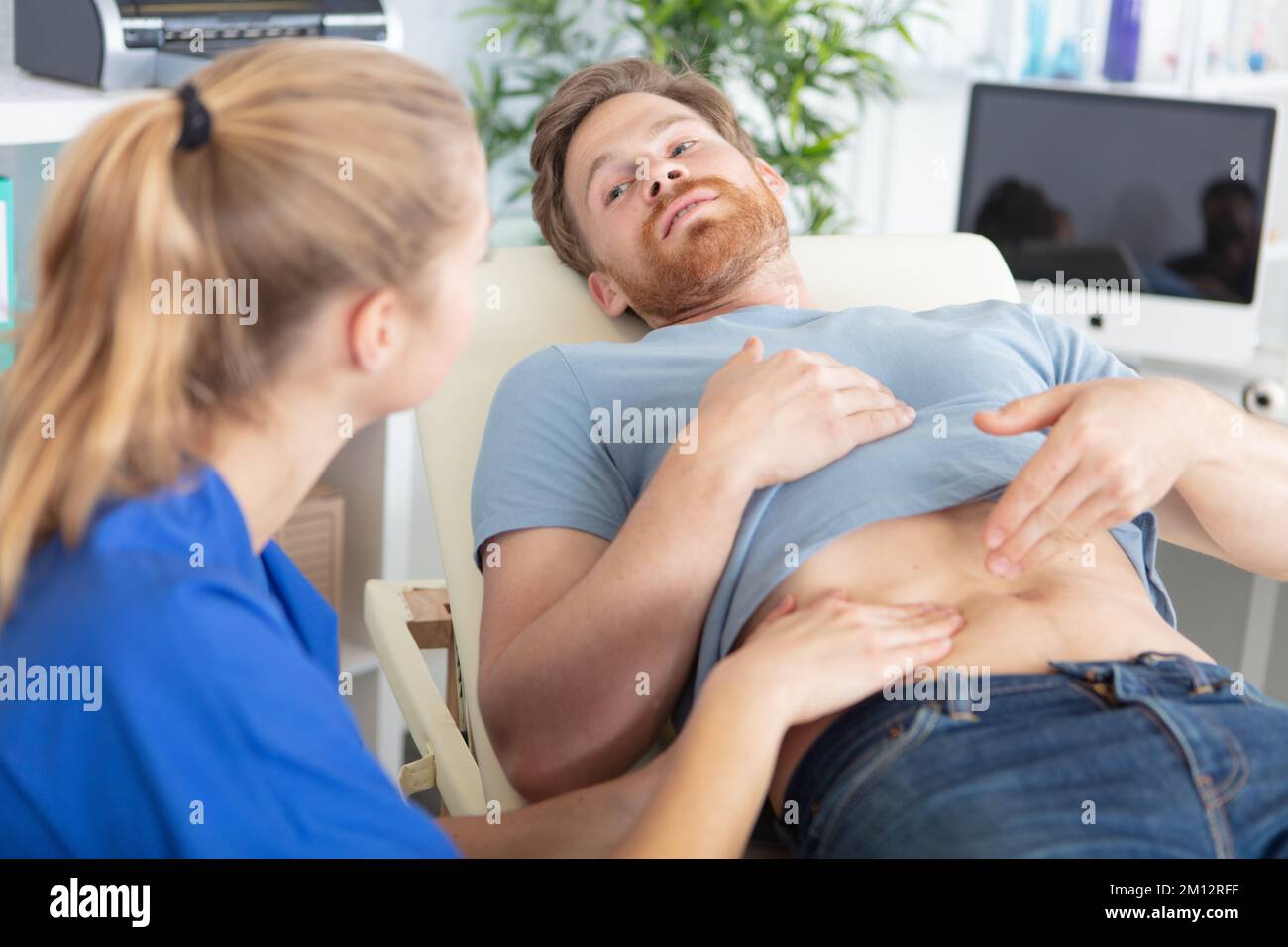 medico che esamina il paziente maschio con dolori di stomaco Foto Stock