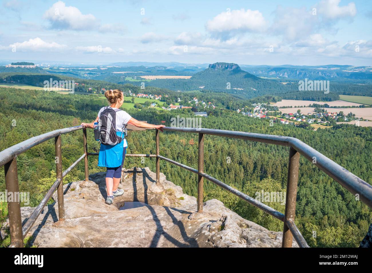 Donna anziana che fa escursioni sulle montagne di arenaria dell'Elba con vista sul Papststein in estate, la Svizzera sassone. Foto Stock