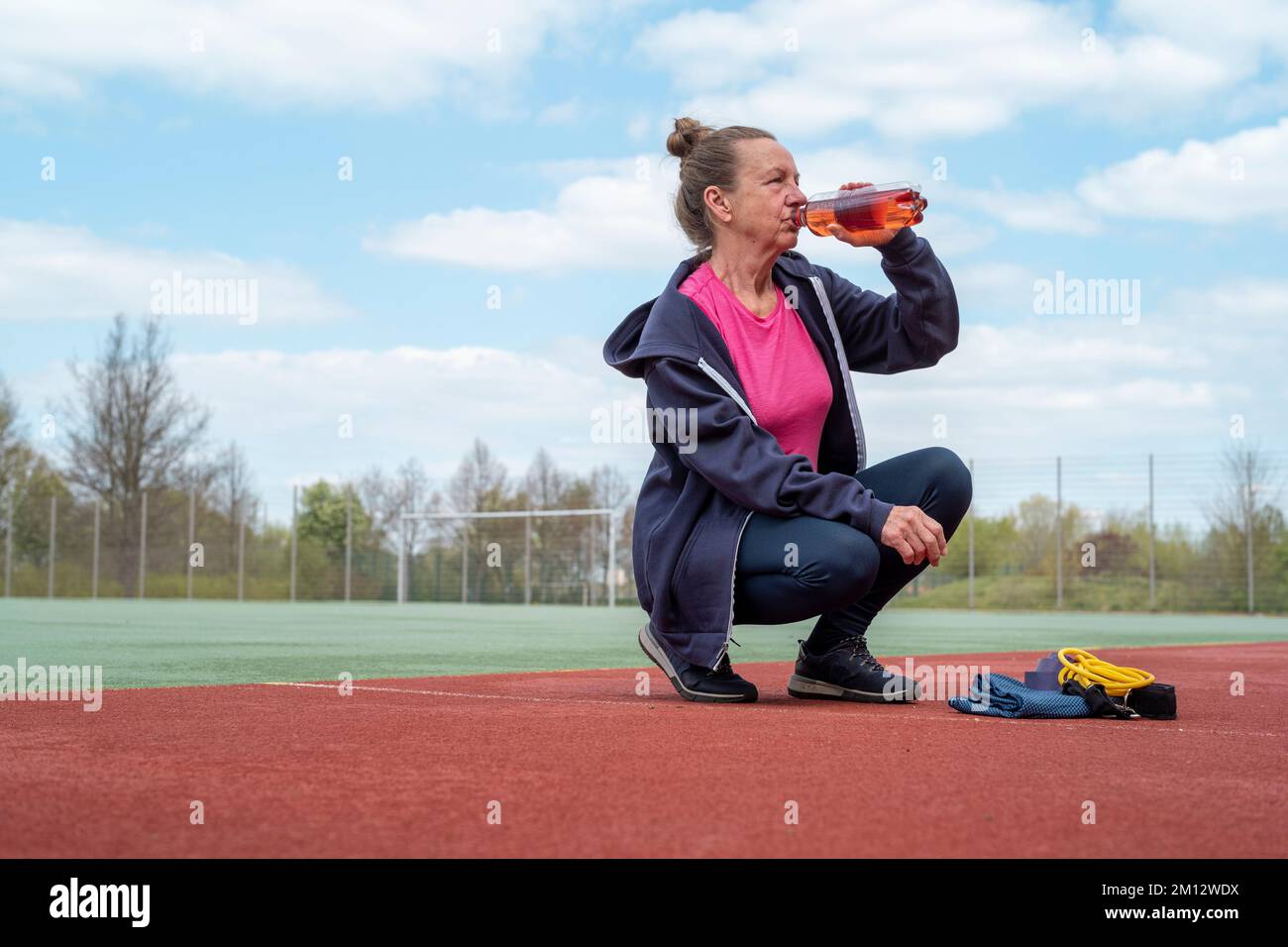 Donna anziana sul campo sportivo durante il giorno in estate. Foto Stock