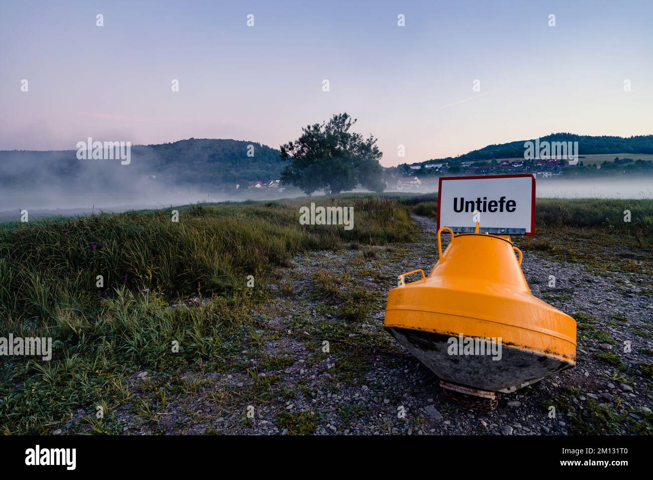 Boa sul fondo asciutto dell'Edersee in Assia in primo piano, sullo sfondo il villaggio Herzhausen nella nebbia Foto Stock