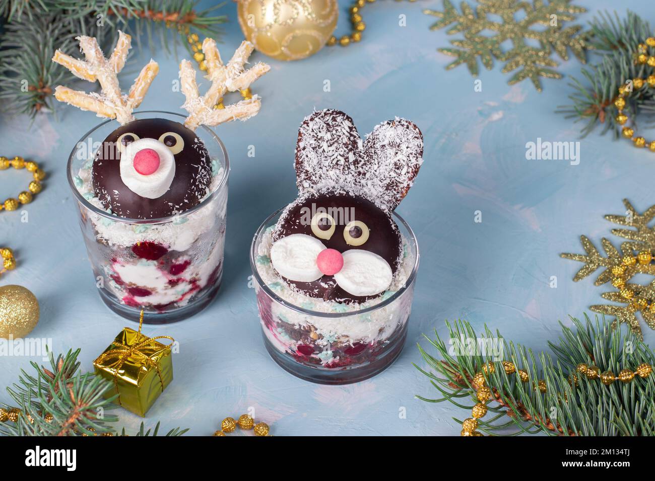 Torta in bicchieri a forma di conigli carini e cervi con ciliegie, biscotto al cioccolato e fiocchi di cocco Foto Stock