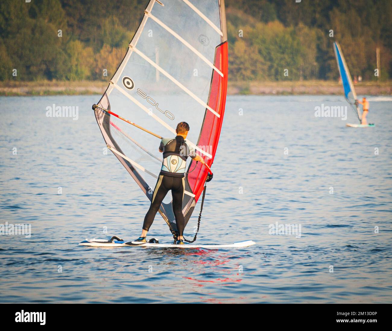 wetsufer vestito sul lago calmo cercando di catturare il vento Foto Stock