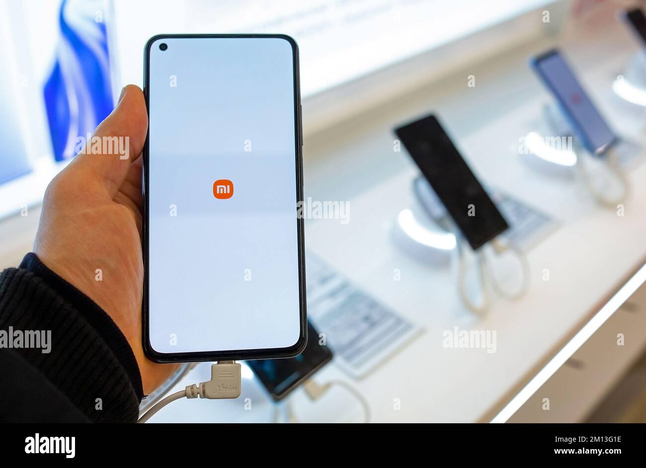 Smartphone con logo Xiaomi sullo schermo in mano. Il cliente sceglie lo smartphone nel negozio di telefoni cellulari Foto Stock