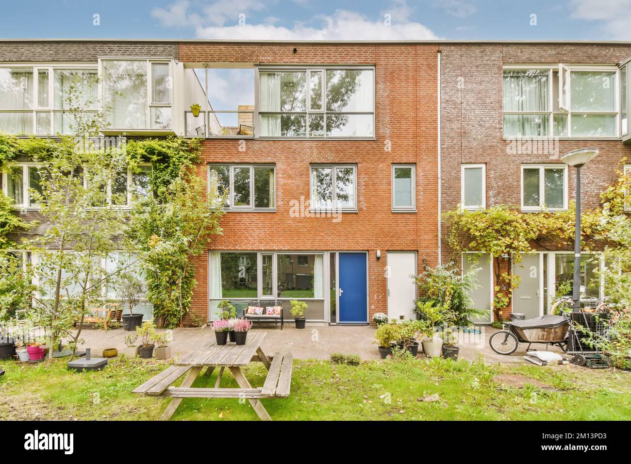 un appartamento nei paesi bassi con molte finestre e piante che crescono sul cortile, c'è una porta blu Foto Stock