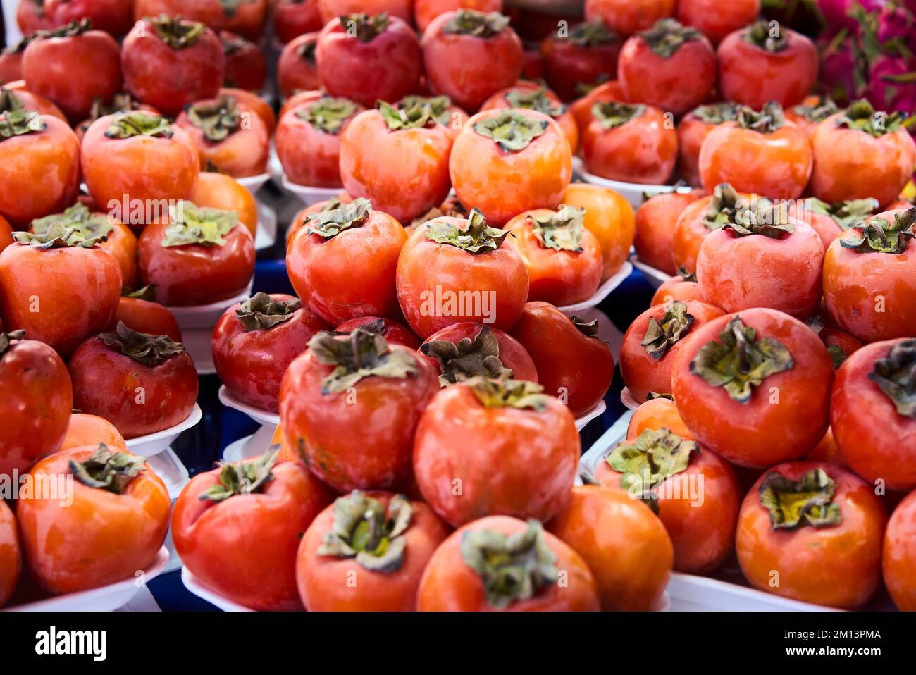 Persimmons freschi maturi nel mercato. Sfondo dei persimmons. Frutta di persimmon biologica in mucchio al mercato locale degli agricoltori. Sfondo dei persimmons. Primo piano Foto Stock
