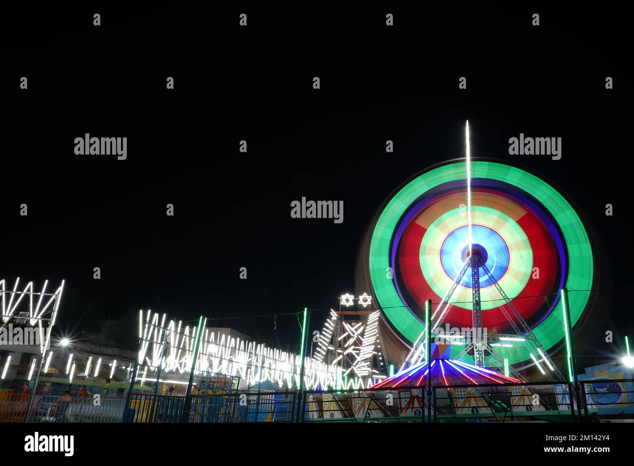 Esposizione lunga velocità dell'otturatore lenta ripresa di una ruota panoramica rotante con belle luci in indian Fun Fair di notte Foto Stock