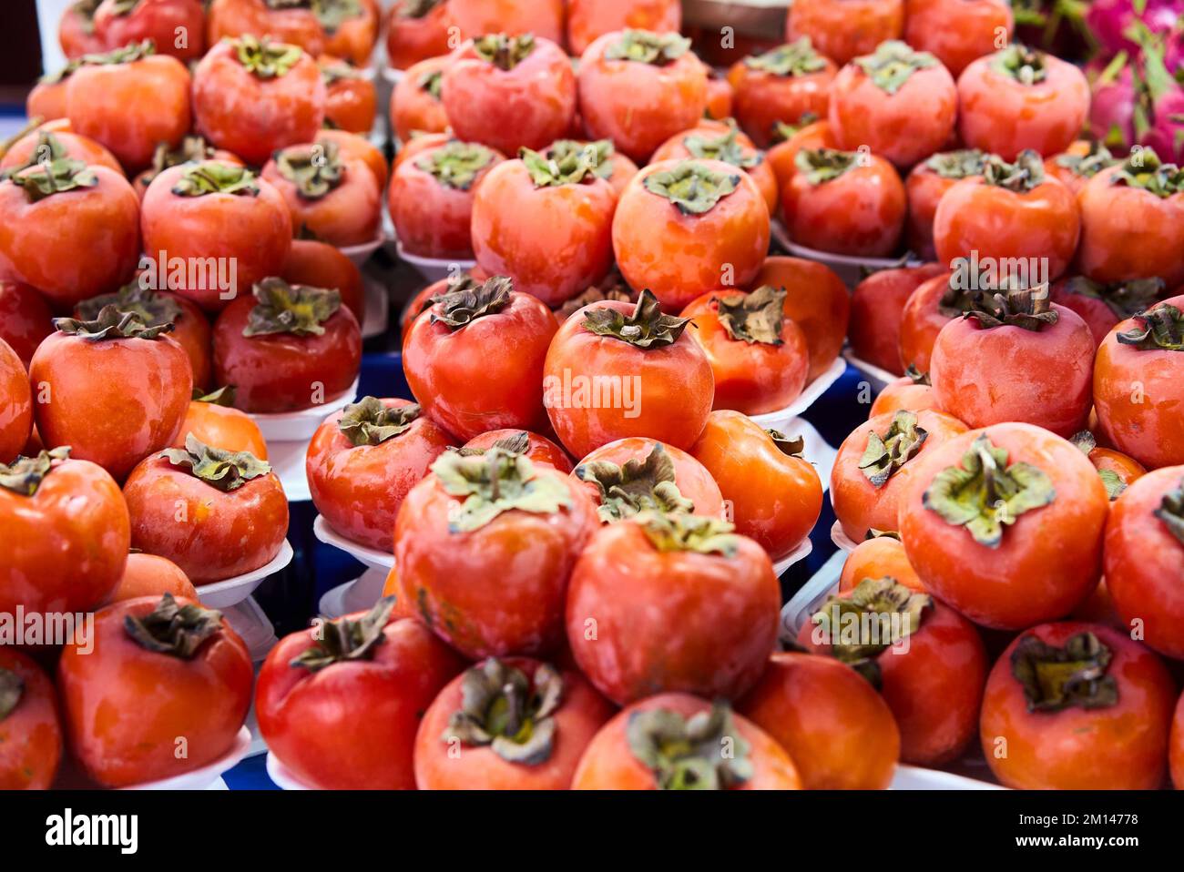 Persimmons freschi maturi nel mercato. Sfondo dei persimmons. Frutta di persimmon biologica in mucchio al mercato locale degli agricoltori. Sfondo dei persimmons. Primo piano Foto Stock