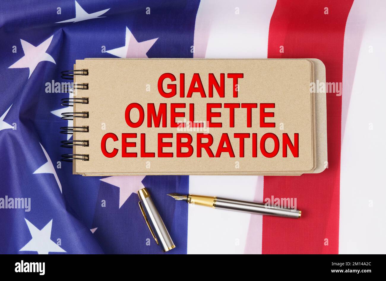 Vacanze USA. Sullo sfondo della bandiera degli Stati Uniti si trova il cartone con l'iscrizione - OMELETTE GIGANTE CELEBRAZIONE Foto Stock