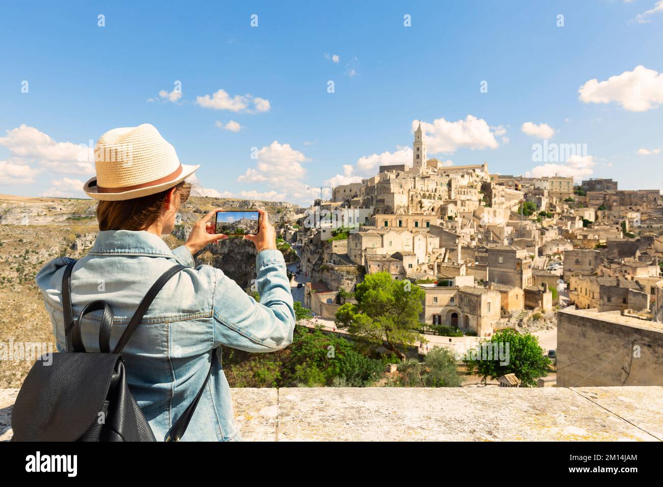 Giovane donna turista fa una foto panoramica dell'antica città di Matera in una giornata di sole, Italia. Foto Stock