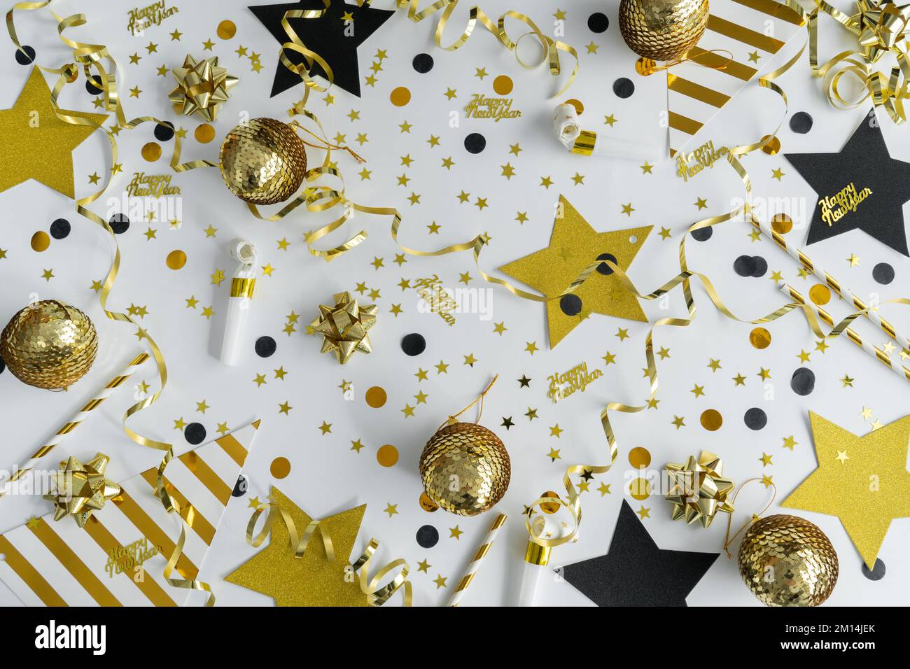Festa di Capodanno. Decorazioni dorate e nere, confetti, streamers, soffiatori a corno. Felice anno nuovo piatto composizione laica. Foto Stock