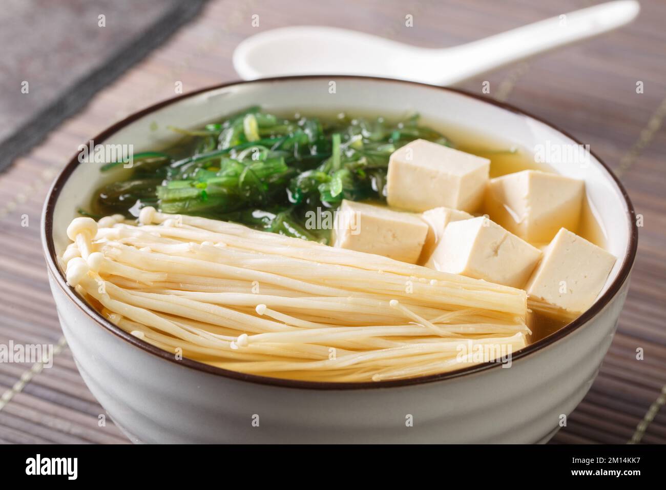 Zuppa di miso fatta in casa con formaggio tofu, funghi enoki, alghe wakame primo piano in una ciotola sul tavolo. Orizzontale Foto Stock