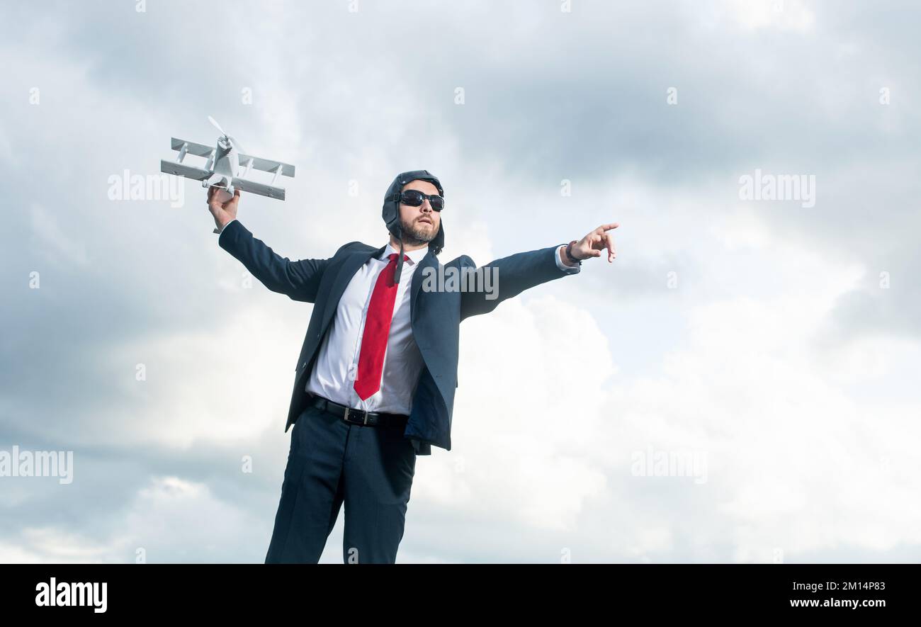 uomo d'affari in tuta e cappello pilota lancio aereo giocattolo su sfondo cielo. aumenta l'idea Foto Stock