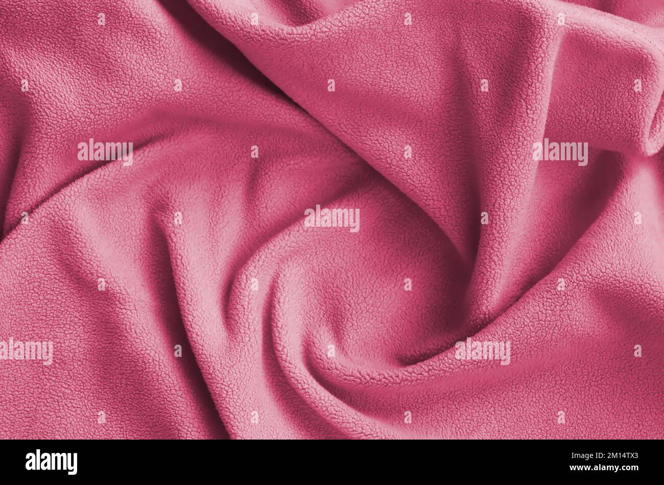 La coperta di tessuto felpato. Uno sfondo di morbido tessuto felpato con un sacco di pieghe in rilievo. Immagine colorata in Viva Magenta, colore del 2023° anno Foto Stock