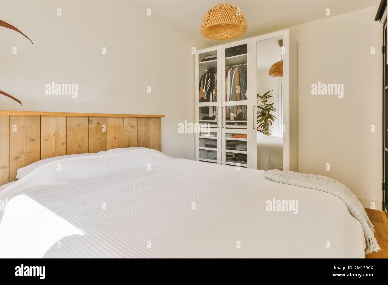 una camera da letto con letti bianchi e testiere in legno è illuminata dalla luce naturale dalla finestra Foto Stock