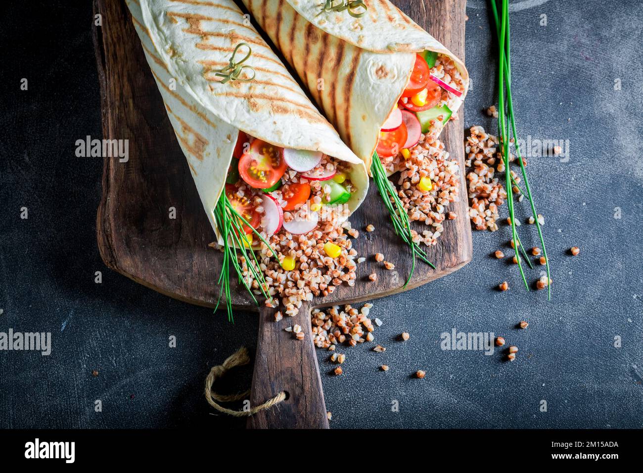 Tortilla vegetariana deliziosa e fresca con semole, pomodori ciliegini e erba cipollina. Tortilla vegetariana con verdure. Foto Stock