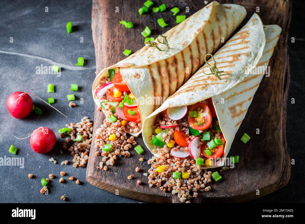 Tortilla vegetariana deliziosa e fresca con semole, rafano e pomodori ciliegini. Tortilla vegetariana con verdure. Foto Stock
