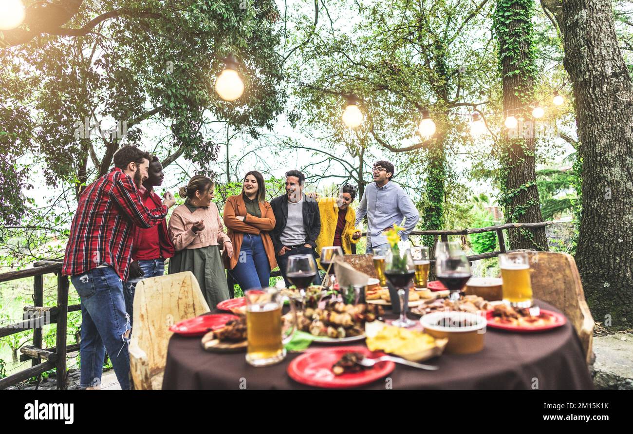 Un grande gruppo di amici in attesa di cena spettacolo in campagna mentre si parla di viaggio estivo Foto Stock