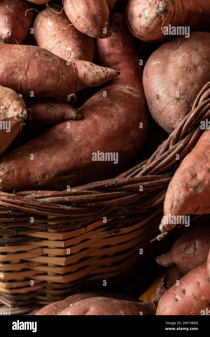 Patate dolci rosse crude messe insieme in un cestino Foto Stock