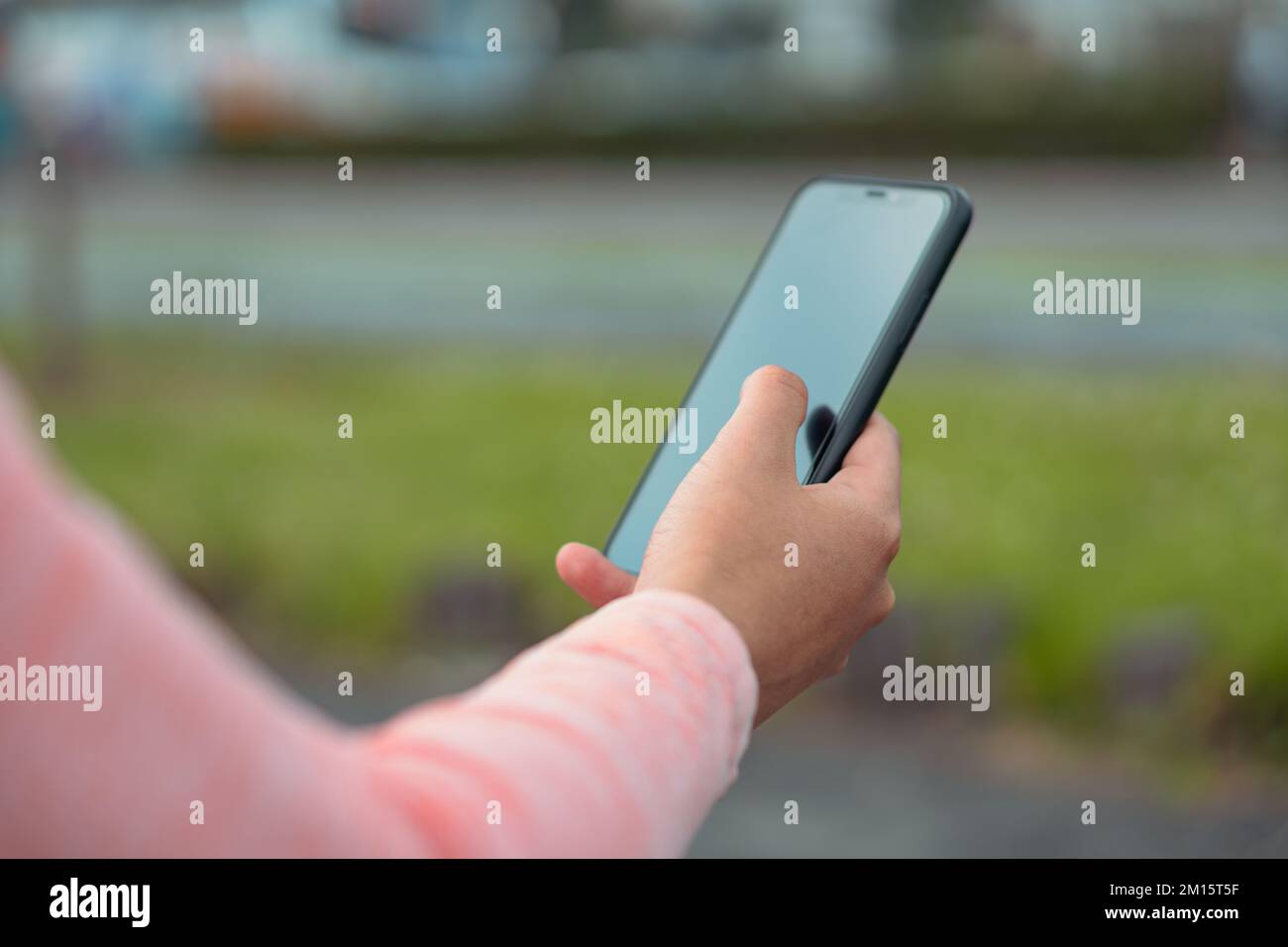 Crop anonima donna in rosa maglione navigazione cellulare navigare su Internet mentre in piedi sulla strada Foto Stock