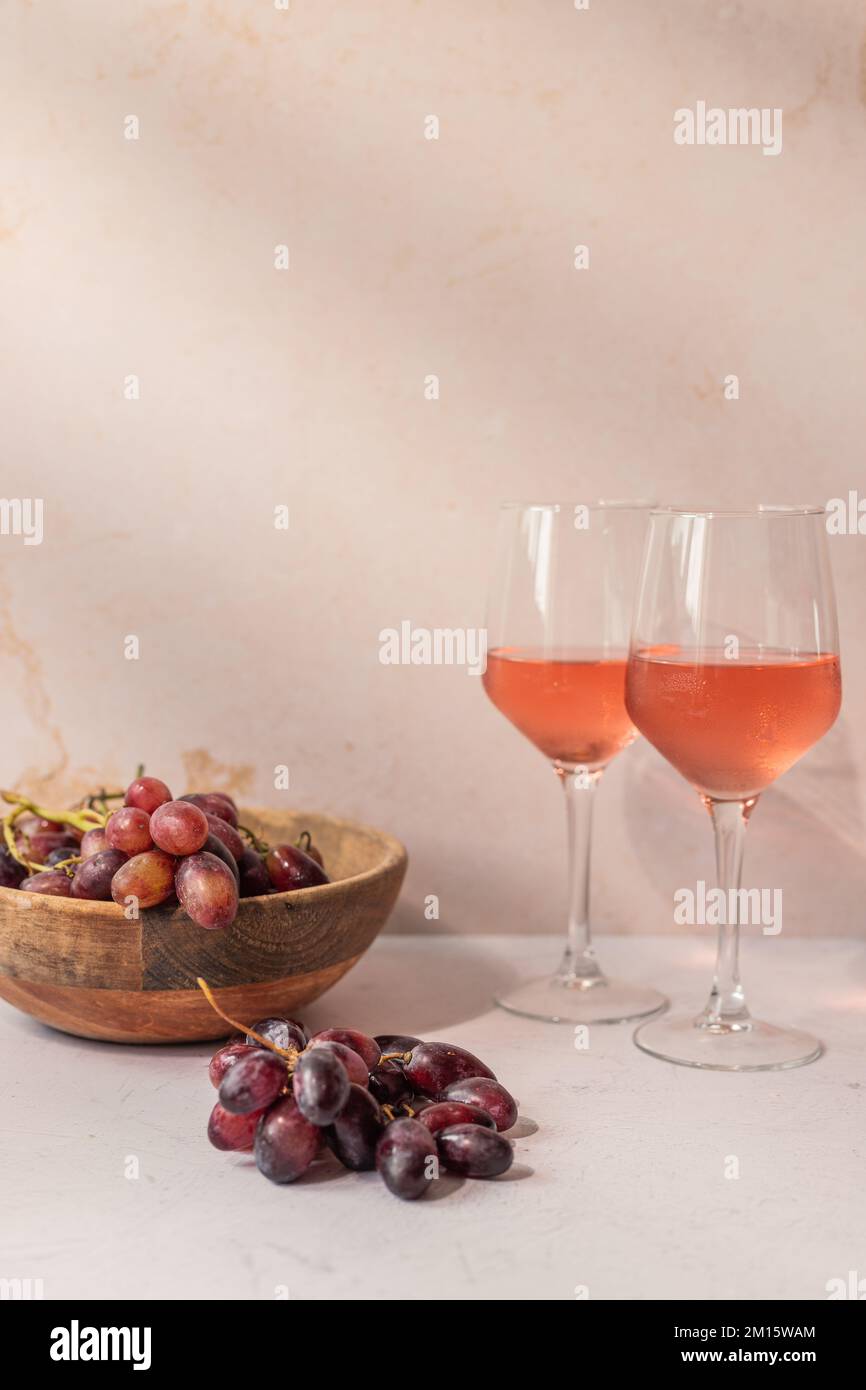 Bicchieri di bevanda rossa posti sul tavolo con ciotola di uva e fichi Foto Stock
