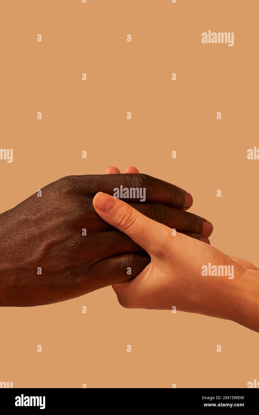Crop anonimo afroamericano uomo tenendo le mani con la donna in studio vicino sfondo rosa Foto Stock