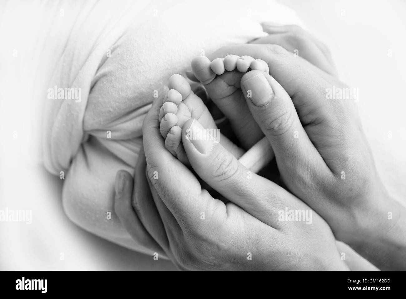 Gambe, dita dei piedi, piedi e talloni di un neonato. Le mani dei genitori tengono le gambe del bambino Foto Stock