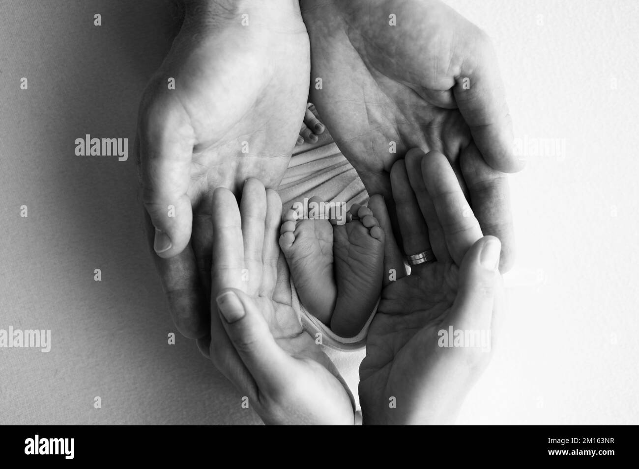 Gambe, dita dei piedi, piedi e talloni di un neonato. Le mani dei genitori tengono le gambe del bambino Foto Stock