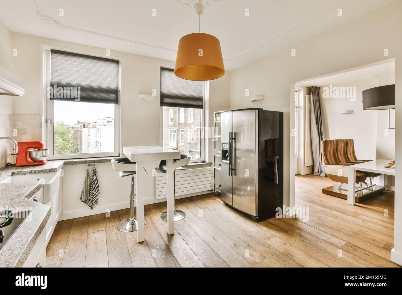 cucina e soggiorno in un appartamento con pavimenti in legno, pareti bianche, pavimenti in parquet e ampie finestre Foto Stock