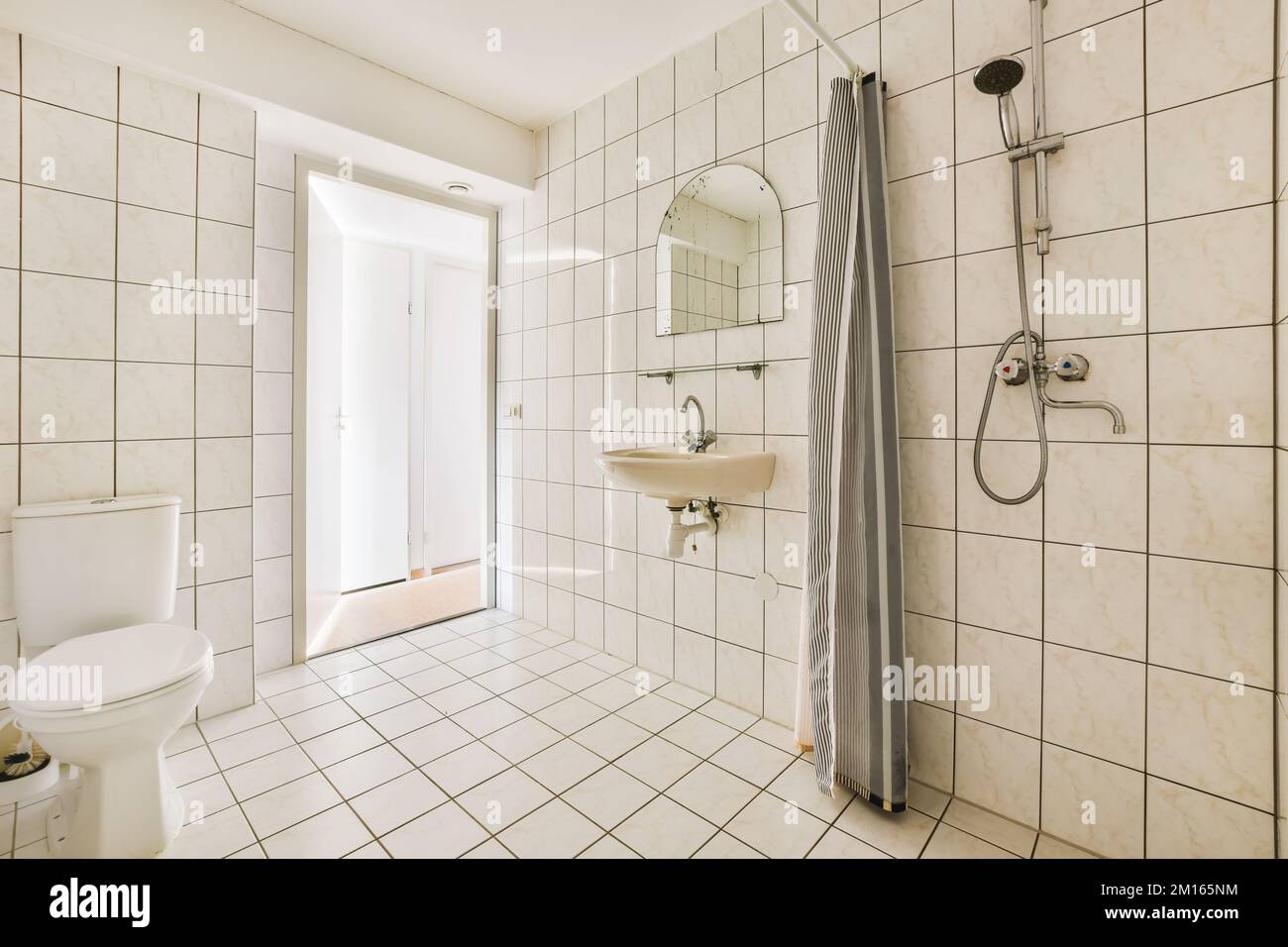 un bagno con piastrelle bianche sulle pareti, e una cabina doccia nell'angolo accanto al water Foto Stock
