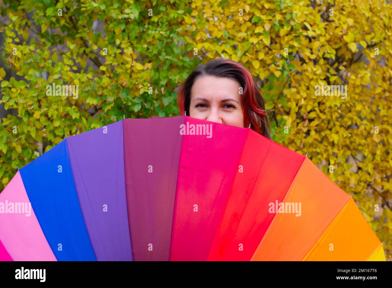 arcobaleno ombrello enorme e una ragazza che peeking fuori Foto Stock