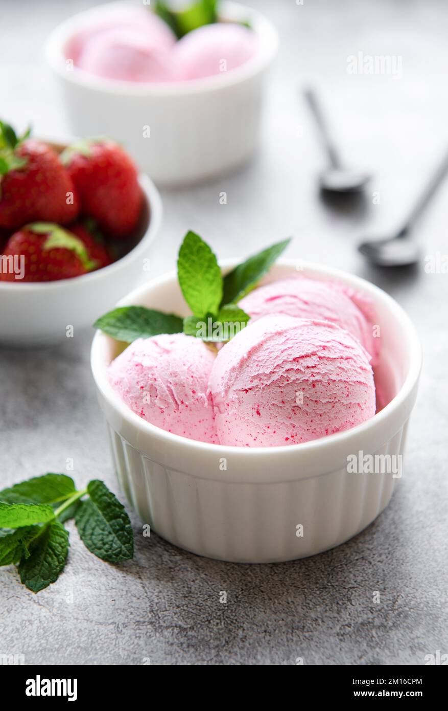 Gelato alla fragola fatto in casa con fragole fresche. Dolce bacche dessert estate. Sfondo concreto Foto Stock