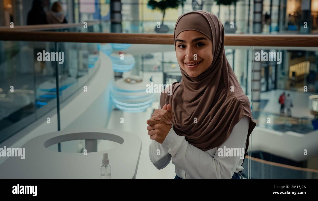 Ragazza studentesca islamica che pulisce le mani da sanitizer al caffè pubblico donna araba in hijab cura salute uso anti spray batterico da coronavirus Foto Stock