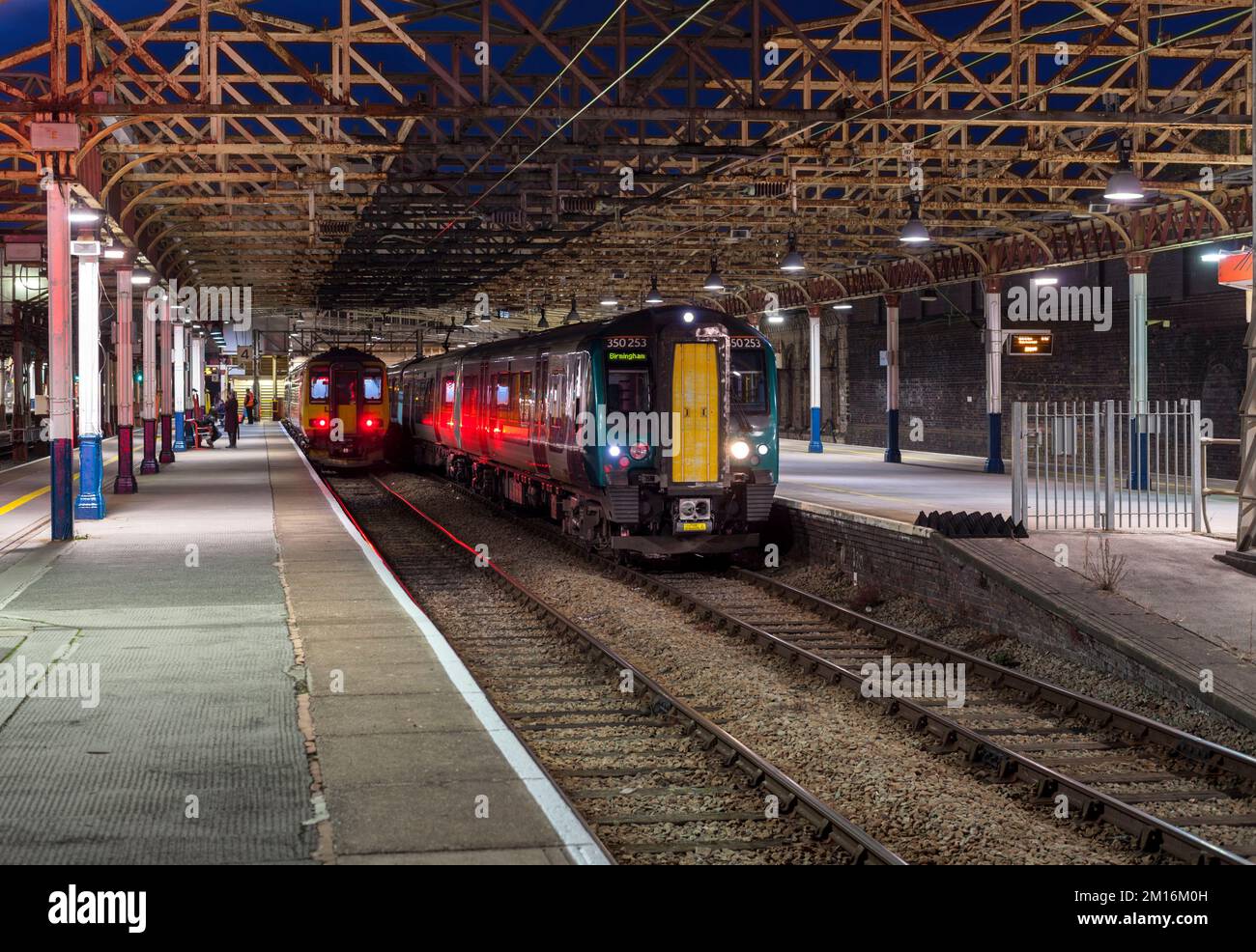 I treni della London North Western Railway e delle East Midlands sono in attesa di partenza dalla stazione ferroviaria di Crewe di notte. Foto Stock