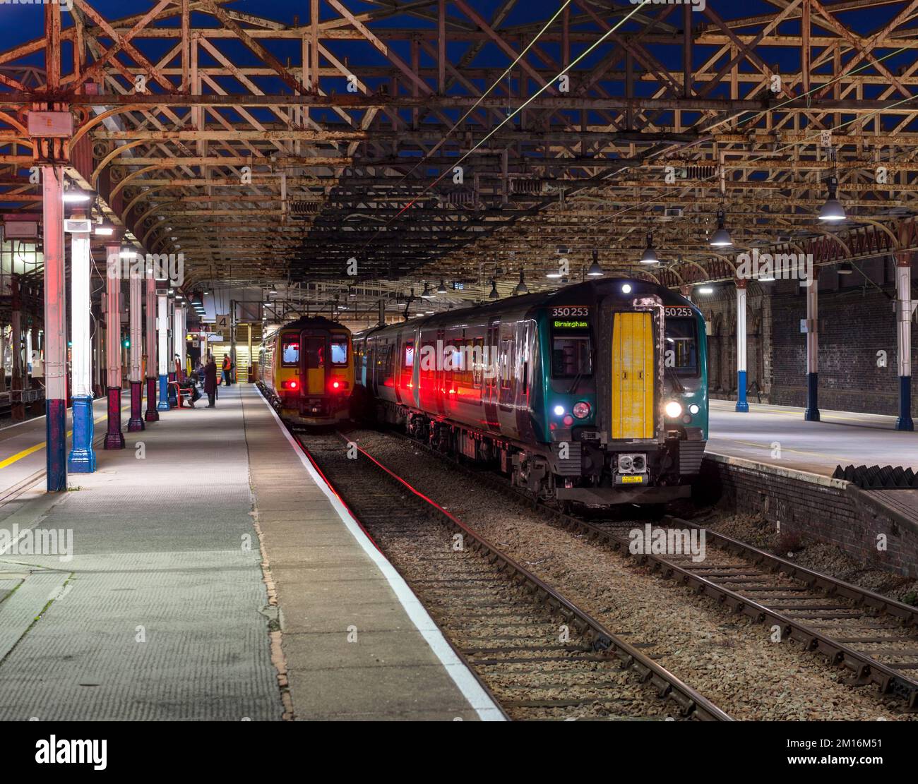I treni della London North Western Railway e delle East Midlands sono in attesa di partenza dalla stazione ferroviaria di Crewe di notte. Foto Stock