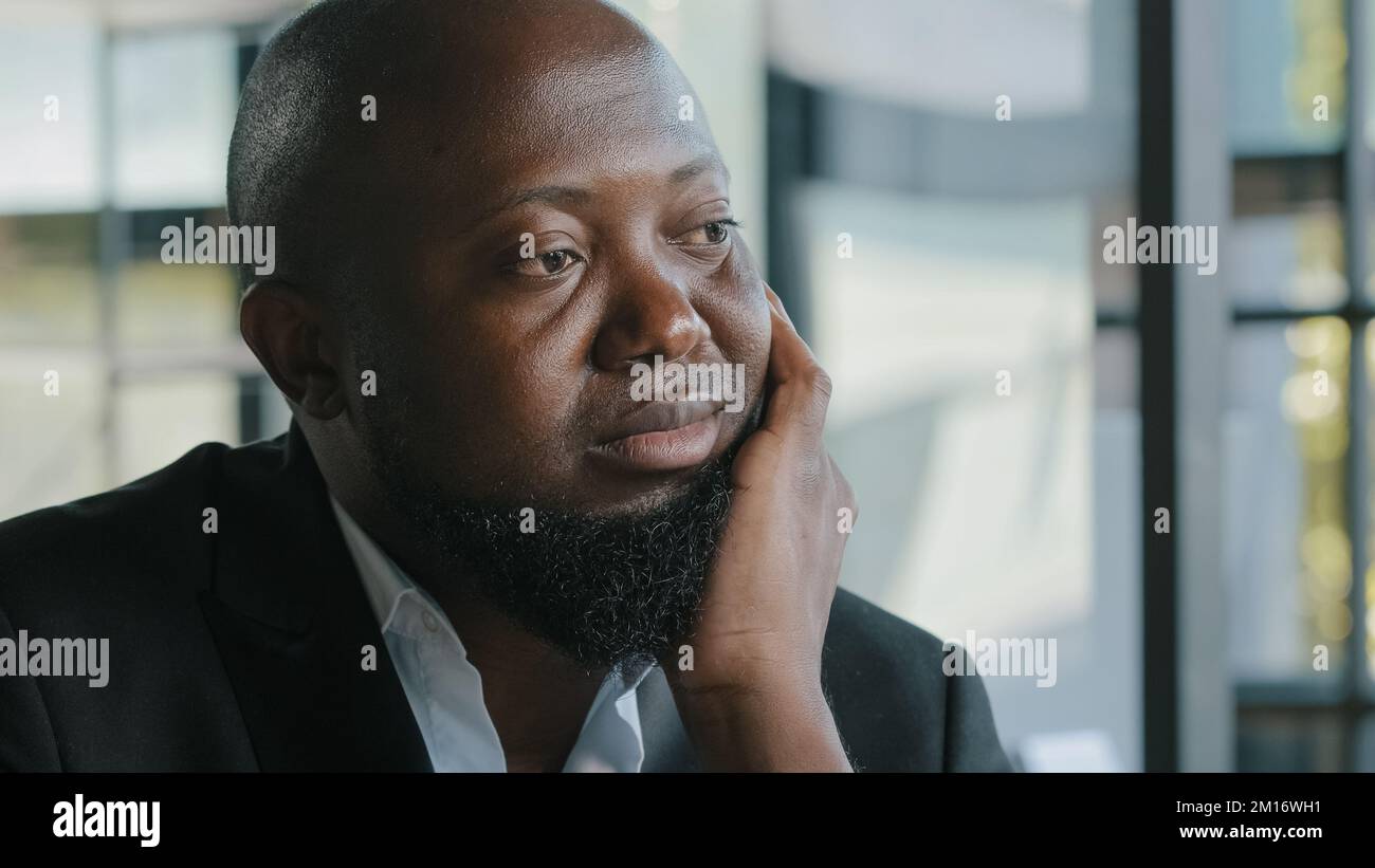Triste infelice afro americano overweight più formato barbuto uomo d'affari tatto noia mancanza di motivazione sedersi in ufficio guardare a distanza sogno abo Foto Stock
