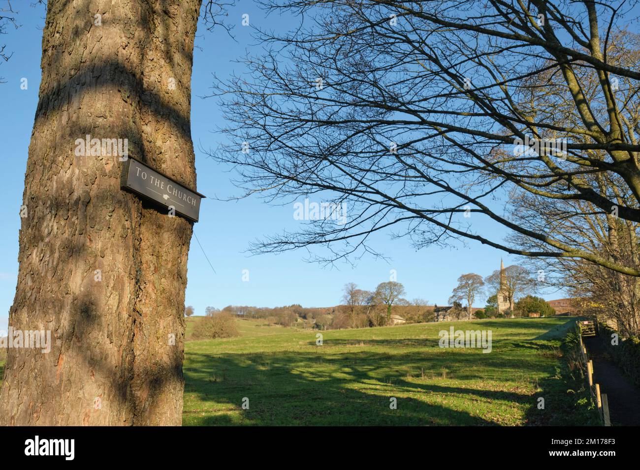 Un cartello fisso su un vecchio albero indica la strada attraverso i campi verso la Chiesa di Hathersage, Derbyshire. Foto Stock Un cartello fisso su un vecchio albero indica la strada attraverso i campi verso la Chiesa di Hathersage, Derbyshire. Foto Stock
