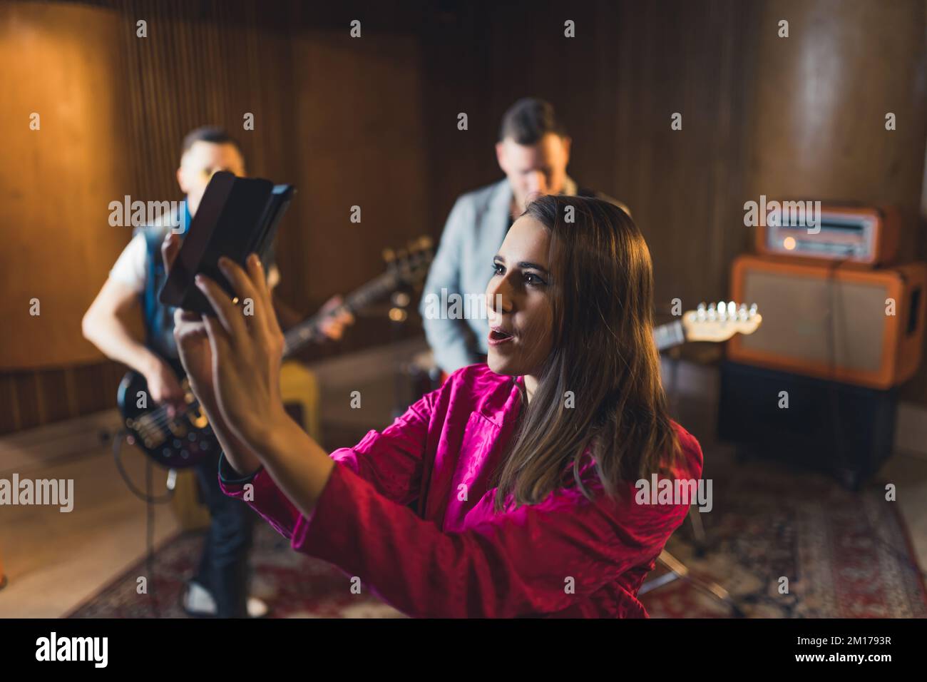 allegra cantante-donna in streaming un video live durante la ripetizione,  altri membri del gruppo nello studio di musica di sottofondo. Foto di alta  qualità Foto stock - Alamy
