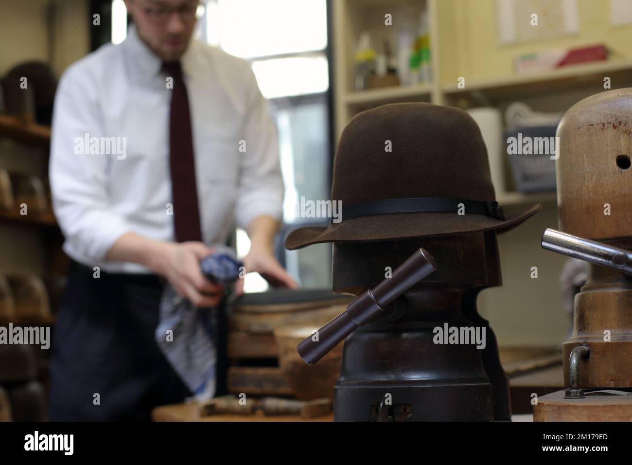 Il membro dello staff di Lock & Co Hatters usa Steam per rimodellare un cappello, Londra, Regno Unito. Foto Stock