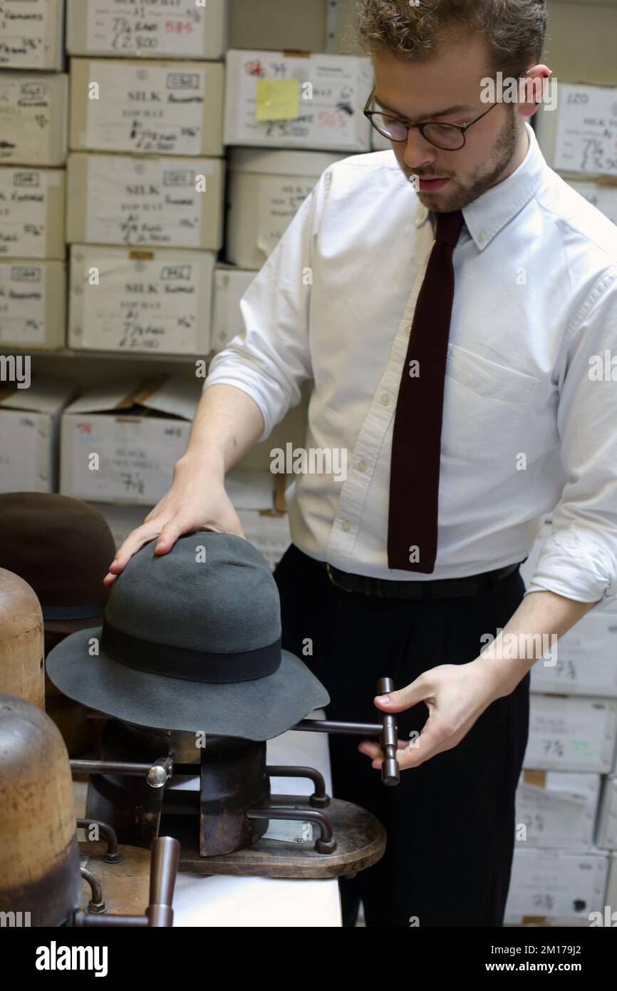 Il membro dello staff di Lock & Co Hatters usa Steam per rimodellare un cappello, Londra, Regno Unito. Foto Stock