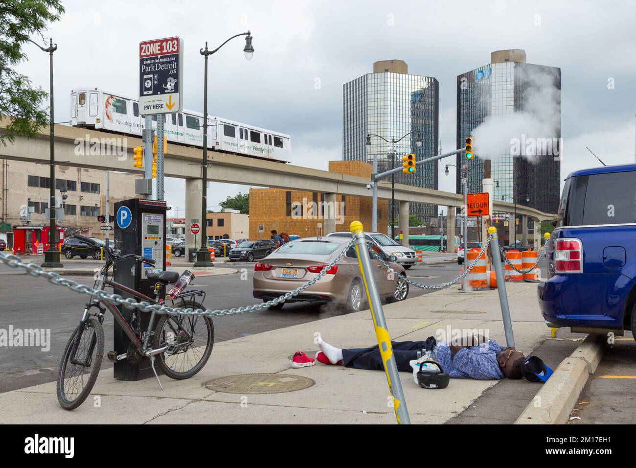 Un uomo con birre e un ghetto-blaster che dorme sul marciapiede Beaubien Boulevard a Detroit vicino alla sede del GM World a Detroit, Michigan, USA. Foto Stock