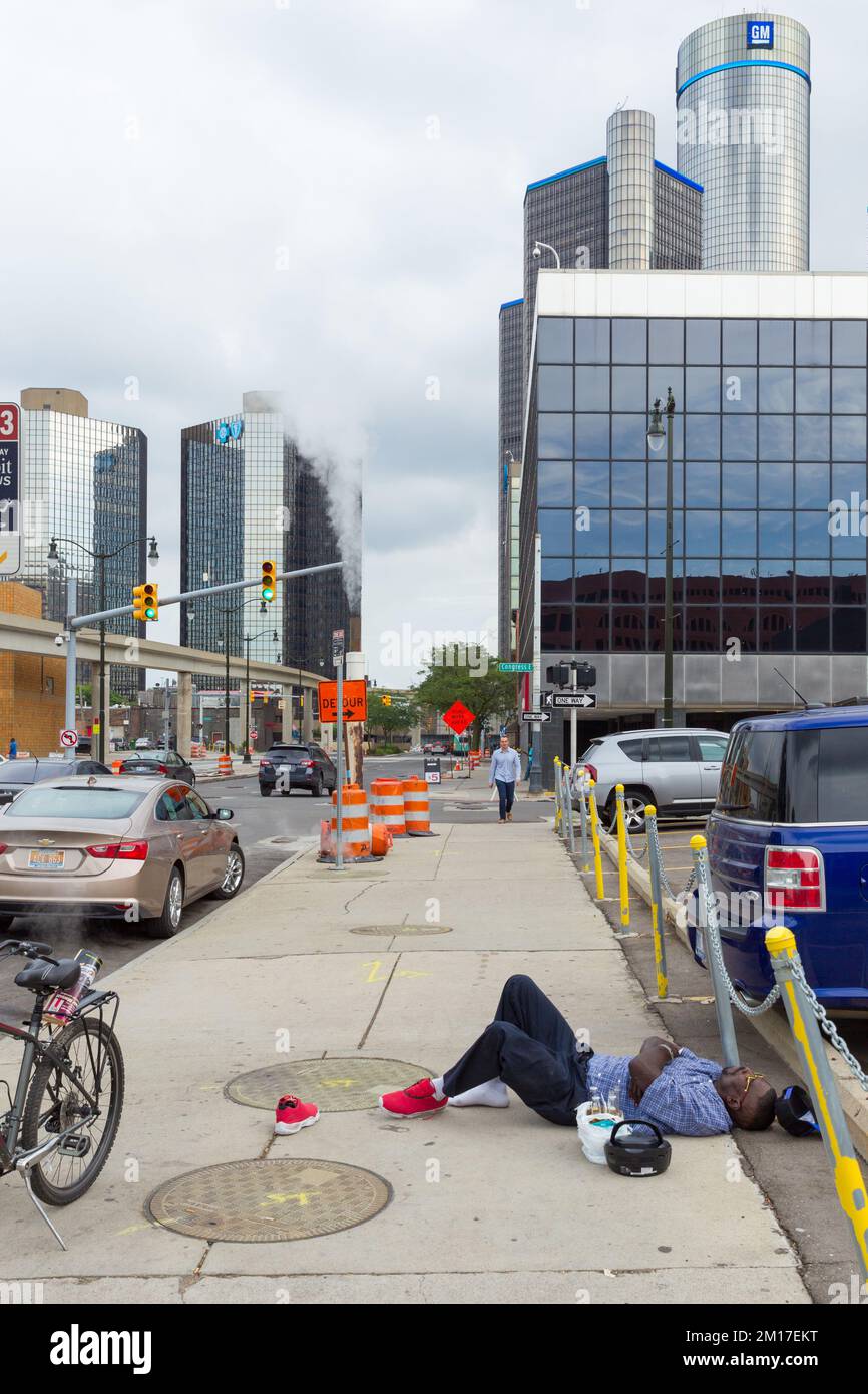 Un uomo con birre e un ghetto-blaster che dorme sul marciapiede Beaubien Boulevard a Detroit vicino alla sede del GM World a Detroit, Michigan, USA. Foto Stock