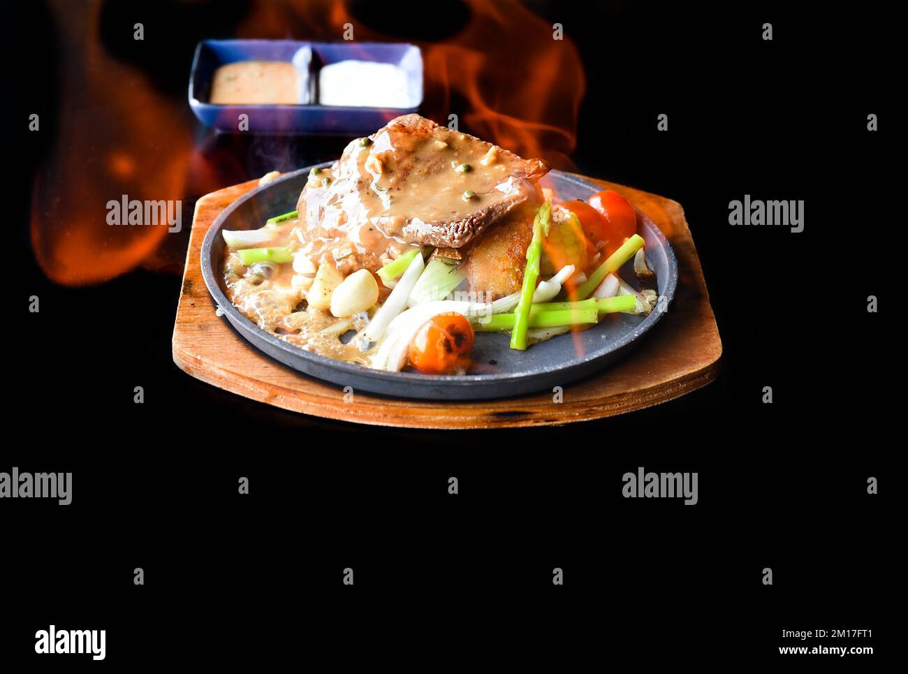 Bistecca di manzo arrosto con verdure e verdure su piatto isolato su sfondo nero vista laterale Foto Stock