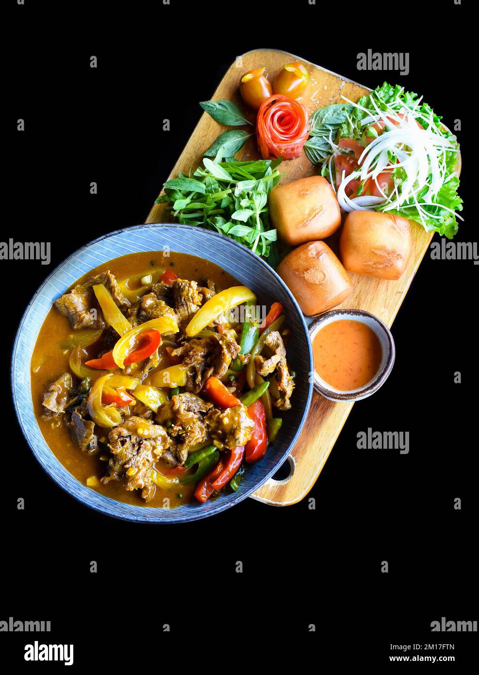 Stufato di manzo con verdure e pane mi banh su tagliere di legno isolato su sfondo nero Foto Stock